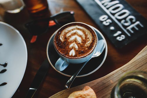 Free High angle of cup of hot cappuccino with latte art placed on table in modern coffee shop Stock Photo