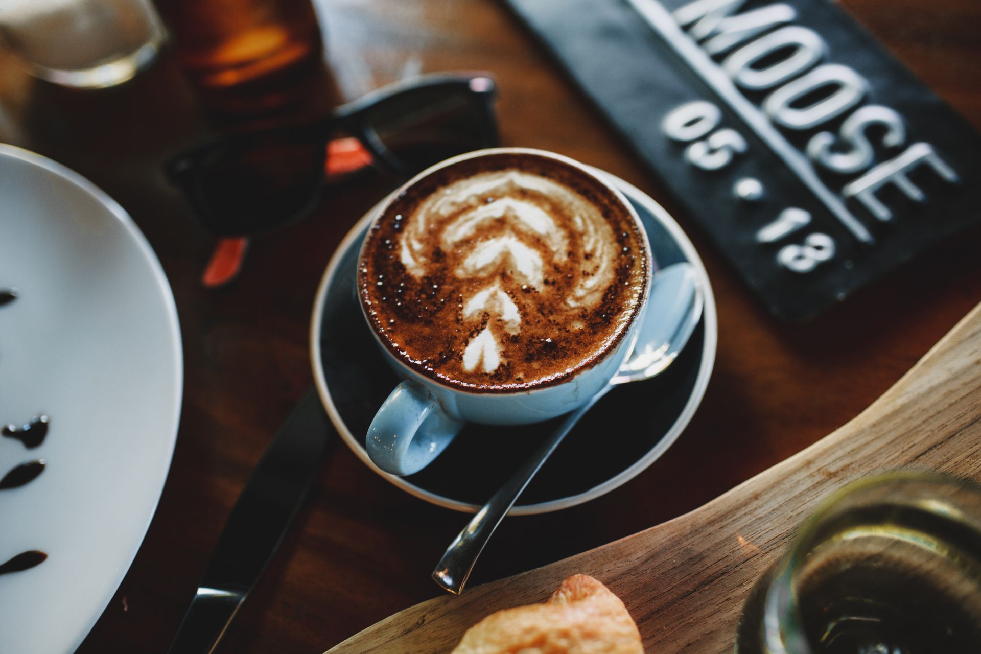 High angle of cup of hot cappuccino with latte art placed on table in modern coffee shop