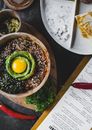 菜单和传统亚洲菜肴附近的桌子上，摆放着一碗异国情调的味噌碗，碗顶配有茄子和鳄梨