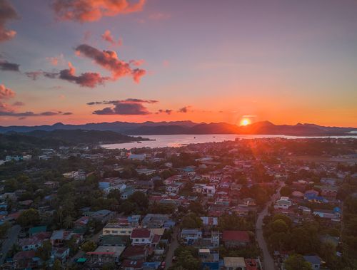Free Peaceful town with traditional houses located on shore of sea surrounded with mountains against picturesque sunset sky Stock Photo