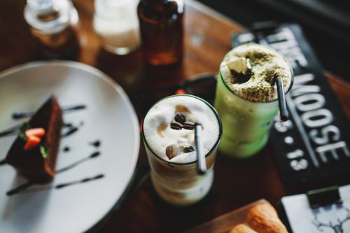Free From above of delicious refreshing assorted milkshakes placed on table in cafe with chocolate cake Stock Photo