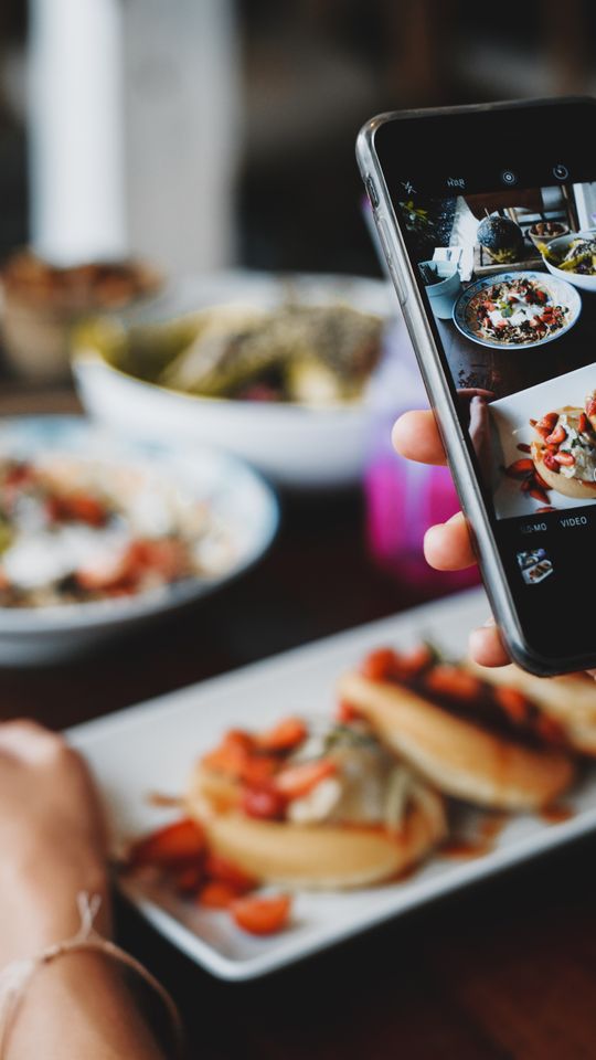 Cliente qui photographie son plat au restaurant