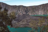 在晴朗的天空下，林贾尼山火山口湖的壮丽景色被周围崎岖的高地环绕