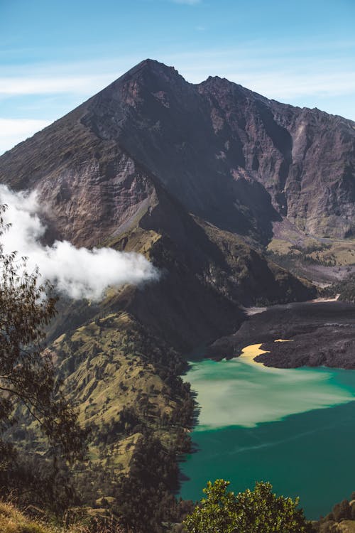 Breathtaking landscape of Rinjani active volcano and crater lake surrounded by rough formations on sunny day