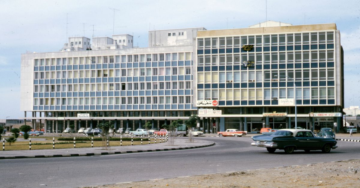 Vintage urban setting featuring mid-century architecture and classic cars during the daytime.