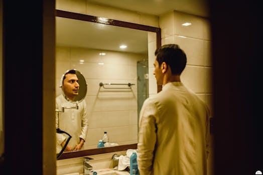 A man stands in front of a bathroom mirror, reflecting on his thoughts.