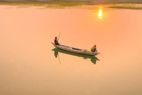 Anonymous fishermen in boat at sundown