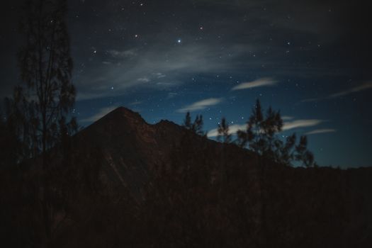 星光灿烂的宁静夜晚，遥远的山峰在多云的暗色天空衬托下，呈现出戏剧性的剪影