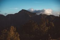 草地山脉雄伟壮丽，风景如画，山峰在厚厚的云层下，映衬着清澈的蓝天