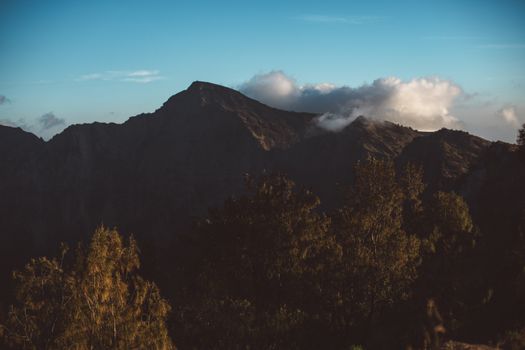 草地山脉雄伟壮丽，风景如画，山峰在厚厚的云层下，映衬着清澈的蓝天