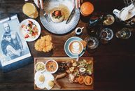 Top view of various dishes and tableware placed on wooden table and crop hands with folk and knife