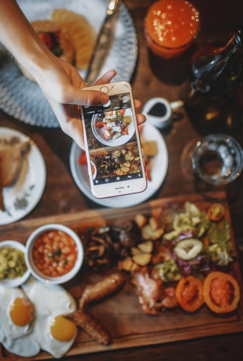 Free Crop person taking photo of delicious breakfast Stock Photo