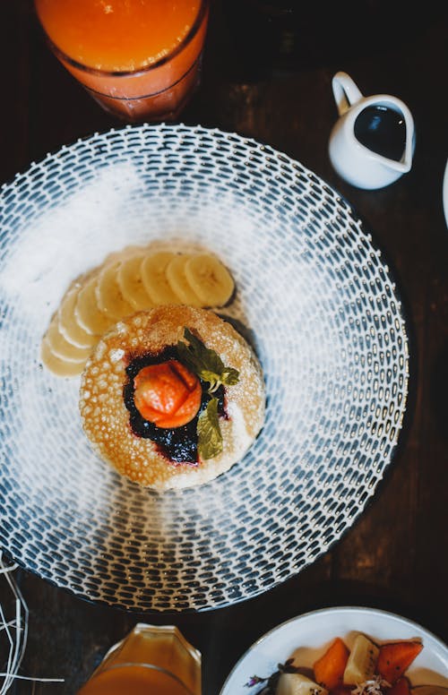 Top view of tasty pancakes with bananas placed on plate on black table