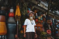 From below of ethnic senior male standing on street market and looking at camera