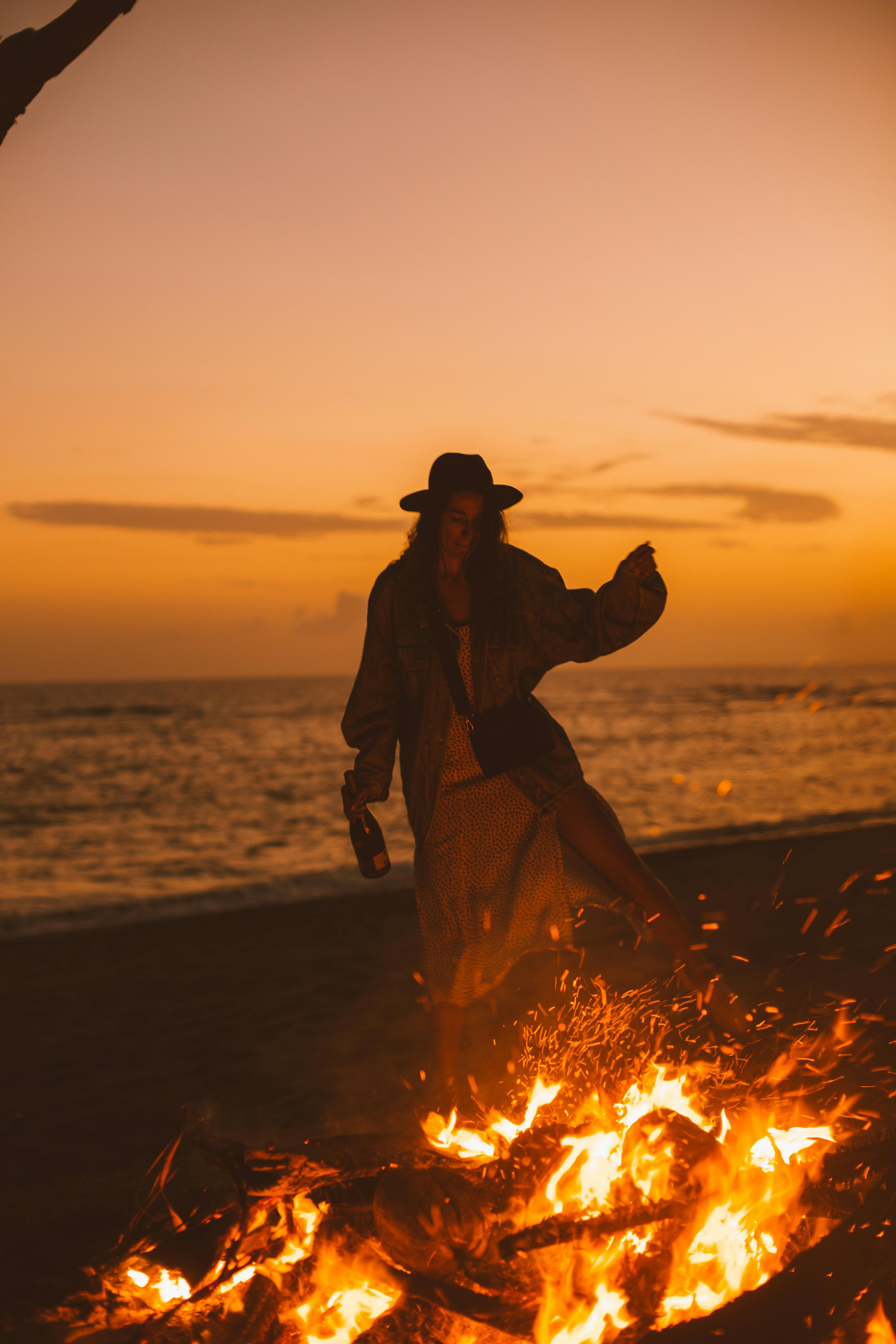 young woman standing near fire and sea