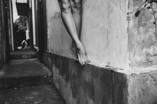 Crop woman standing on wall border of building