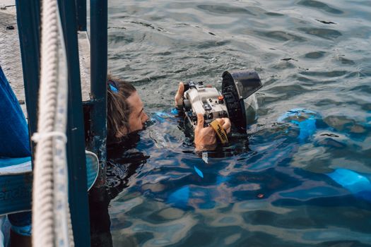 Photographer holding camera in water, capturing ocean scenes.