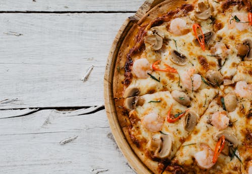 Appetizing pizza with shrimps and champignon on wooden table