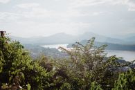 从上方俯瞰，风景如画，宽阔平静的河流在多云的天空下流淌，山上覆盖着绿色的森林