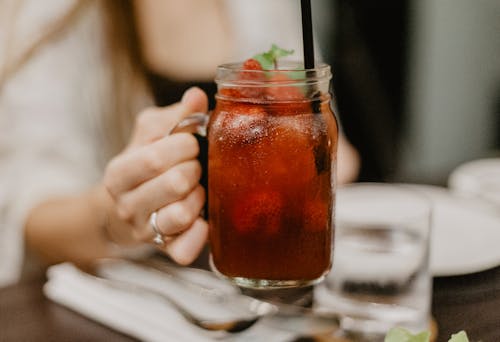 Crop female drinking cold beverage in bar