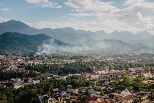 Drone view of picturesque valley with village located near mountain range against blue sky with fluffy clouds on sunny summer day