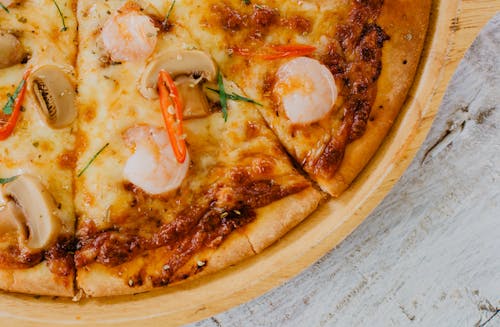 Appetizing baked sliced seafood pizza with mushrooms