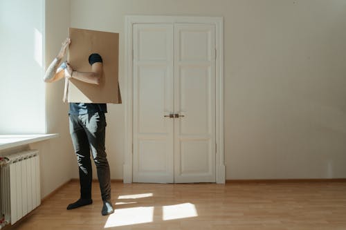 Free Woman in Black Tank Top and Blue Denim Jeans Standing Beside White Wooden Door Stock Photo