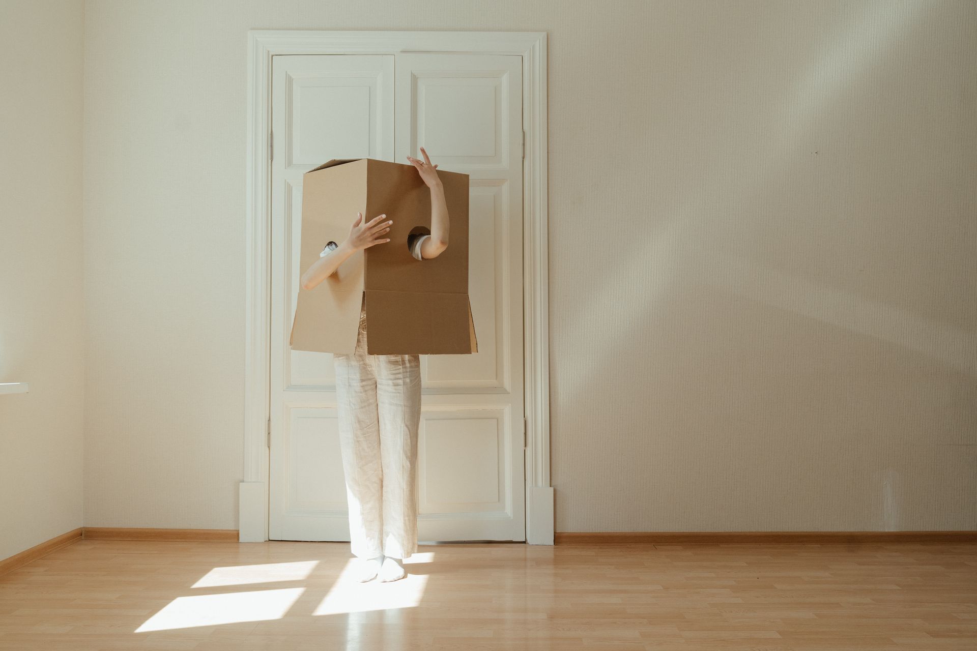 Woman in White Long Sleeve Shirt and White Pants Standing on Brown Wooden Floor