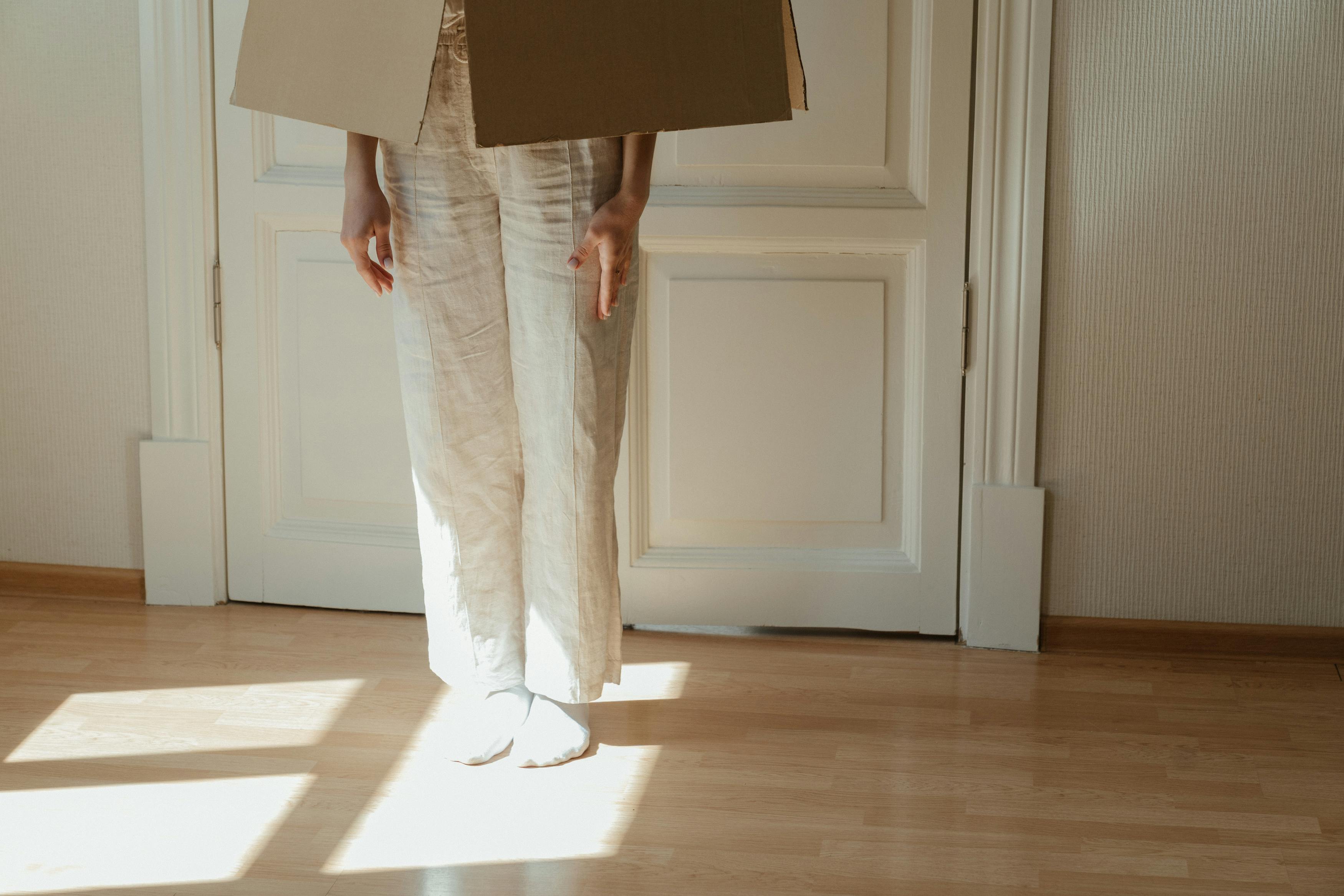 person in white pants and white shoes standing on brown wooden floor