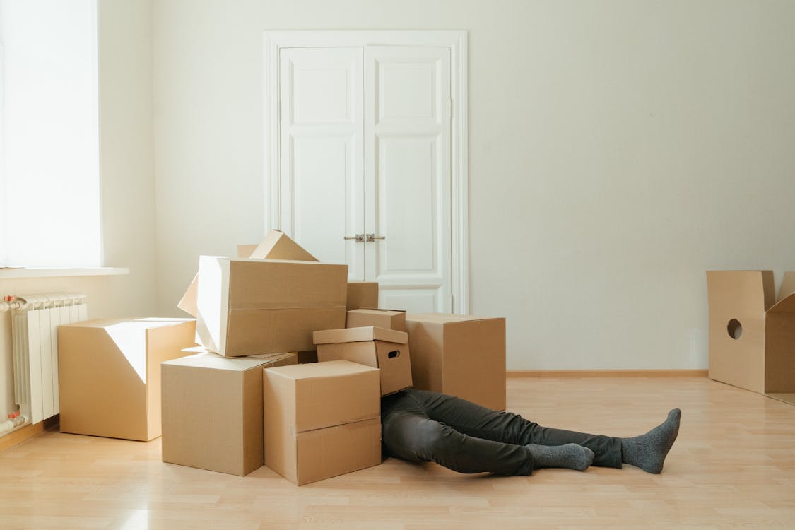 Free Person in Black Leather Boots Lying on Brown Cardboard Boxes Stock Photo