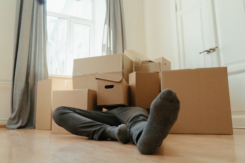 Free Person in Black Pants Sitting on Brown Cardboard Box Stock Photo