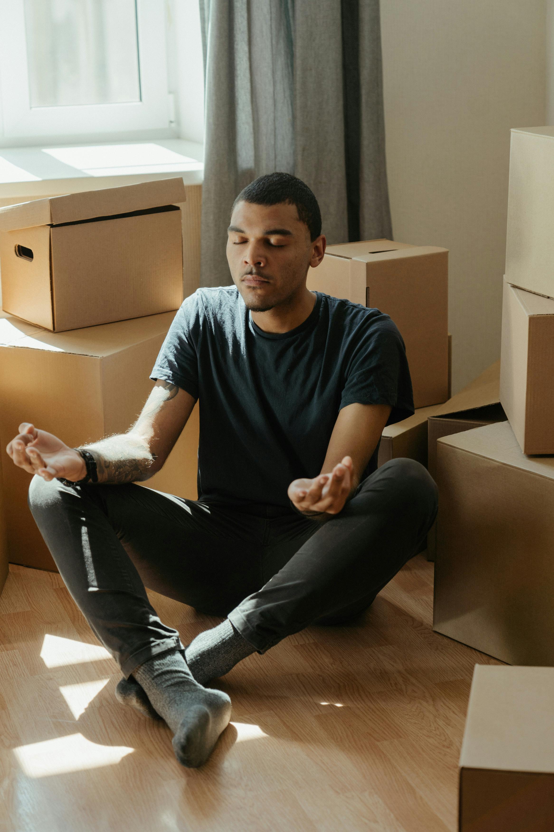 man in blue crew neck t shirt and black pants sitting on brown wooden table