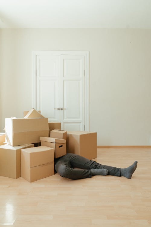 Free Person in Black Leather Boots Sitting on Brown Cardboard Boxes Stock Photo