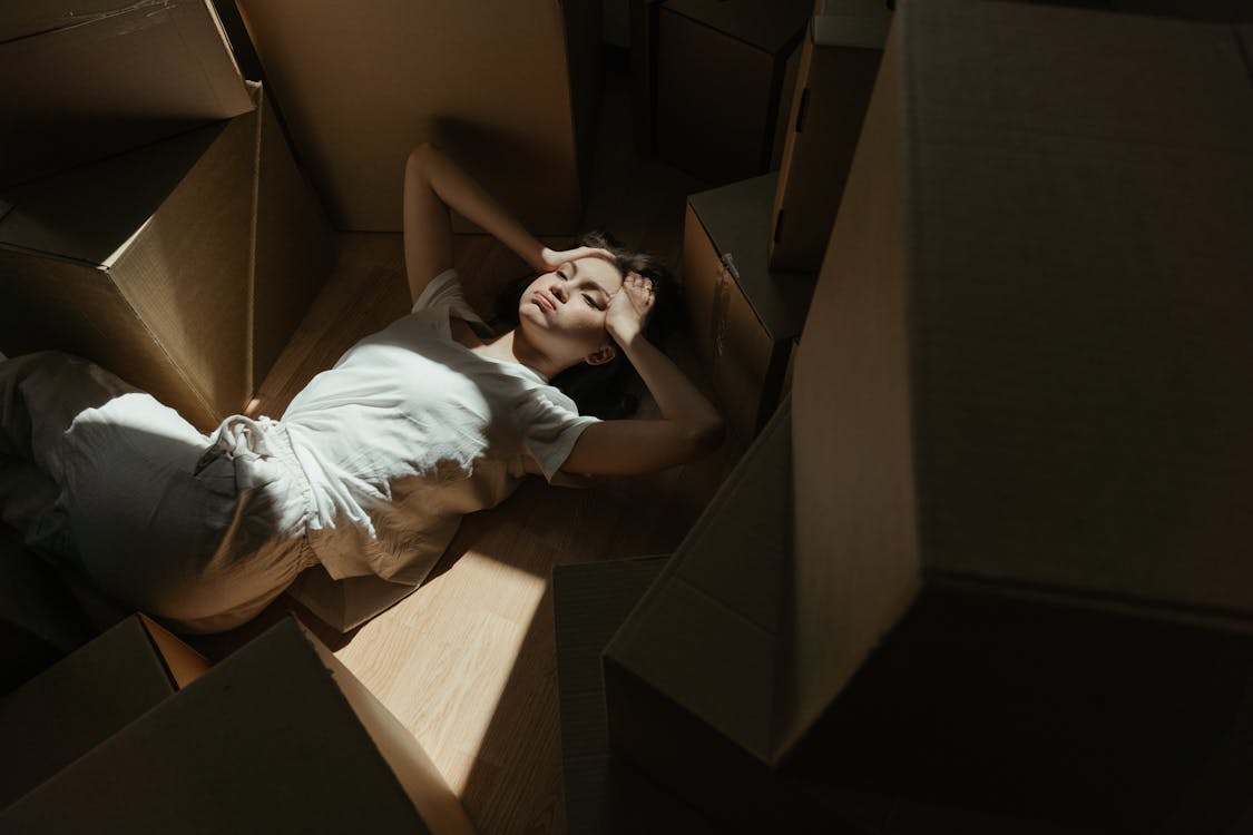 Free Woman in White T-shirt Lying on Brown Cardboard Box Stock Photo
