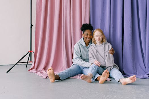 一对跨种族夫妇坐在挂着彩色窗帘的工作室里微笑