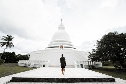 A man walks towards a serene white temple under a cloudy sky, embodying tranquility and exploration.