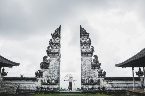 Free Full length back view of unrecognizable person in traditional costume standing with arms outstretched standing at ancient gates of Pura Luhur Lempuyang Temple aka Gates of Heaven in Bali Stock Photo