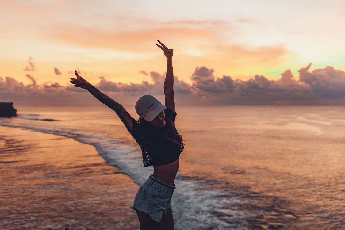 woman in casual shorts and cap enjoying evening on seashore