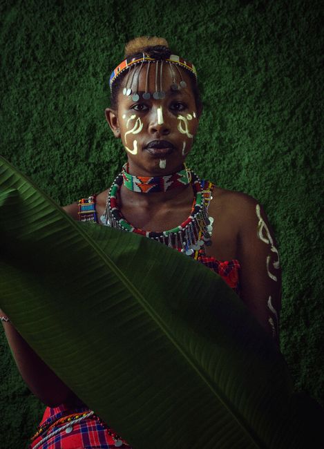 Striking portrait of a woman in traditional Kenyan attire with vibrant face paint and tribal accessories.