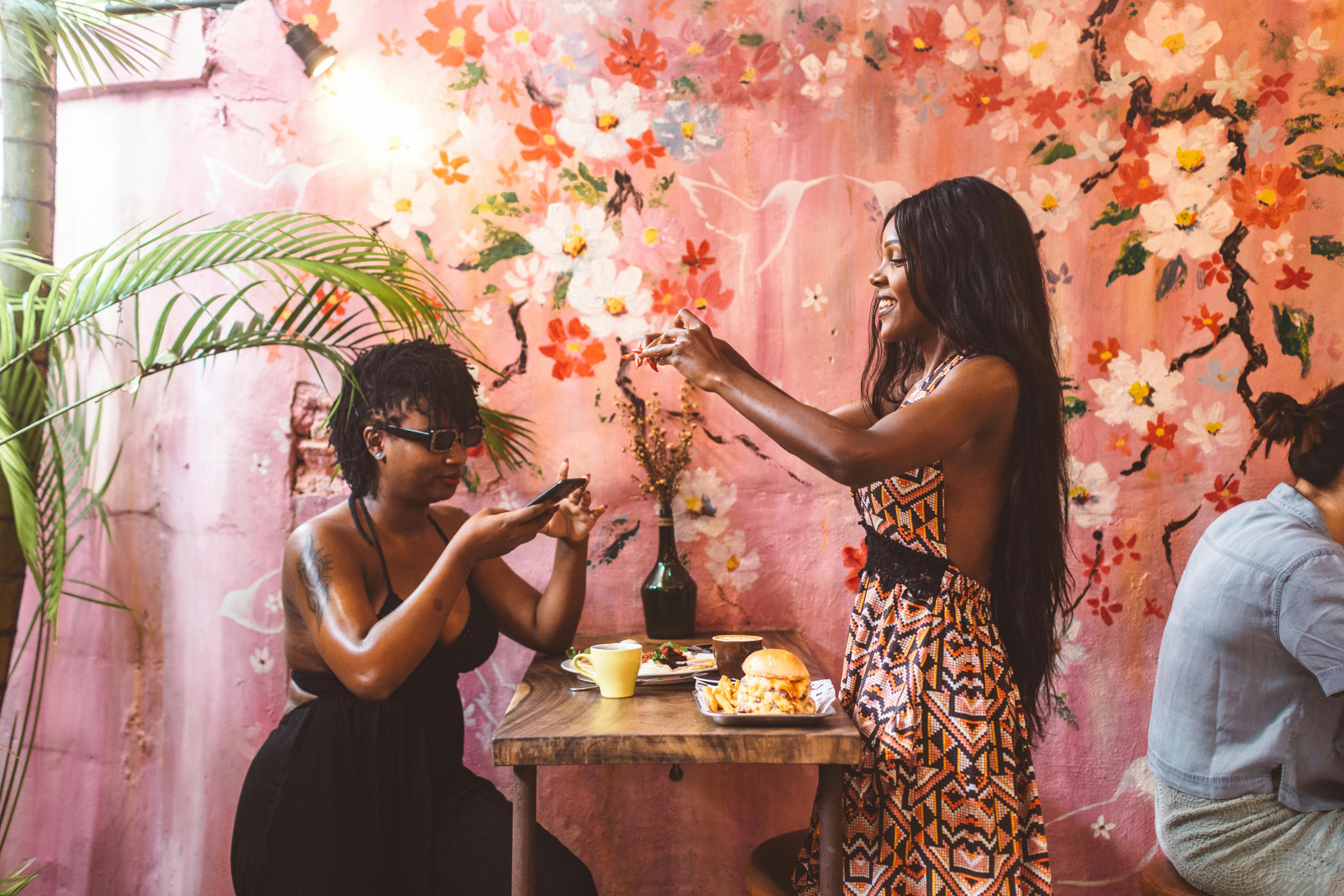 cheerful black women taking pictures on food on smartphone