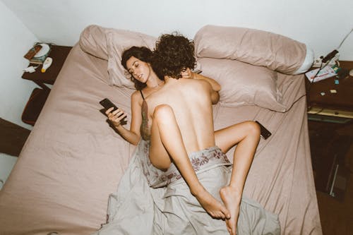 Sexy couple in bed scrolling phones