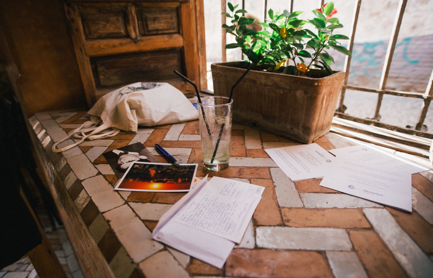 A cozy, rustic indoor scene with scattered envelopes, postcards, and potted plant by window.