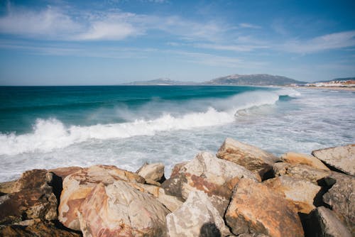 Waves running on rocky coast against blue sky