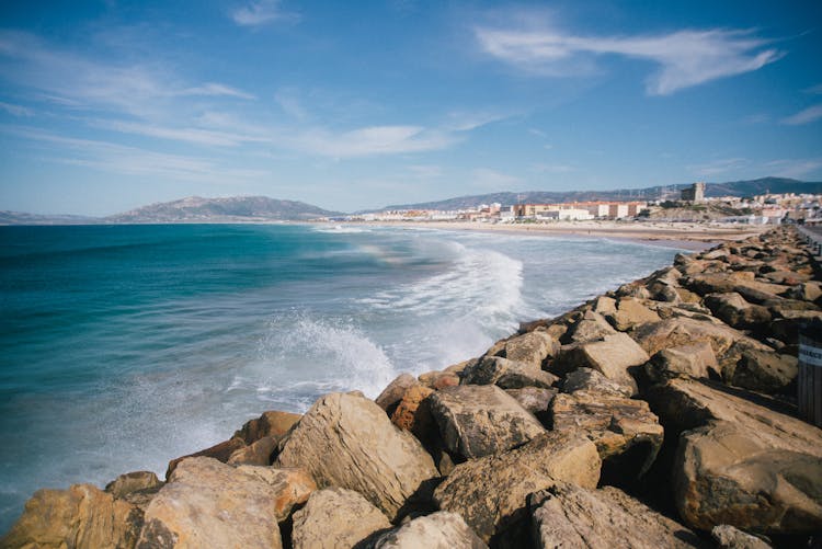 Rocky Coastline Against Blue Sky Near Small Town