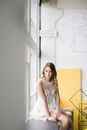 Woman in White Lace Dress Sitting Next to the Glass Window