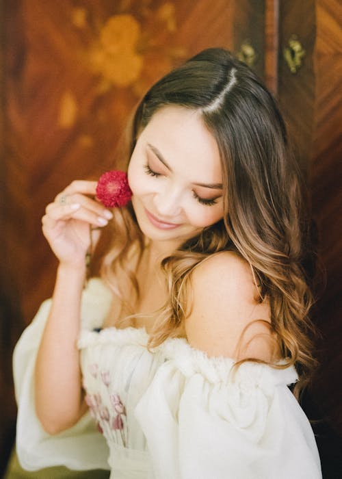 Woman in White Off Shoulder Top Holding a Red Flower
