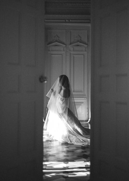 бесплатная Женщина в белом свадебном платье стоит перед дверью Стоковое фото