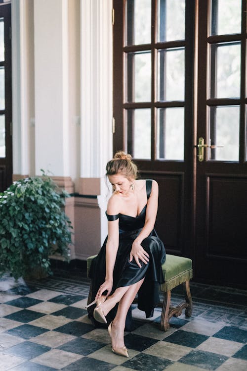 Free Woman in Black Dress Sitting on Brown Wooden Chair Stock Photo