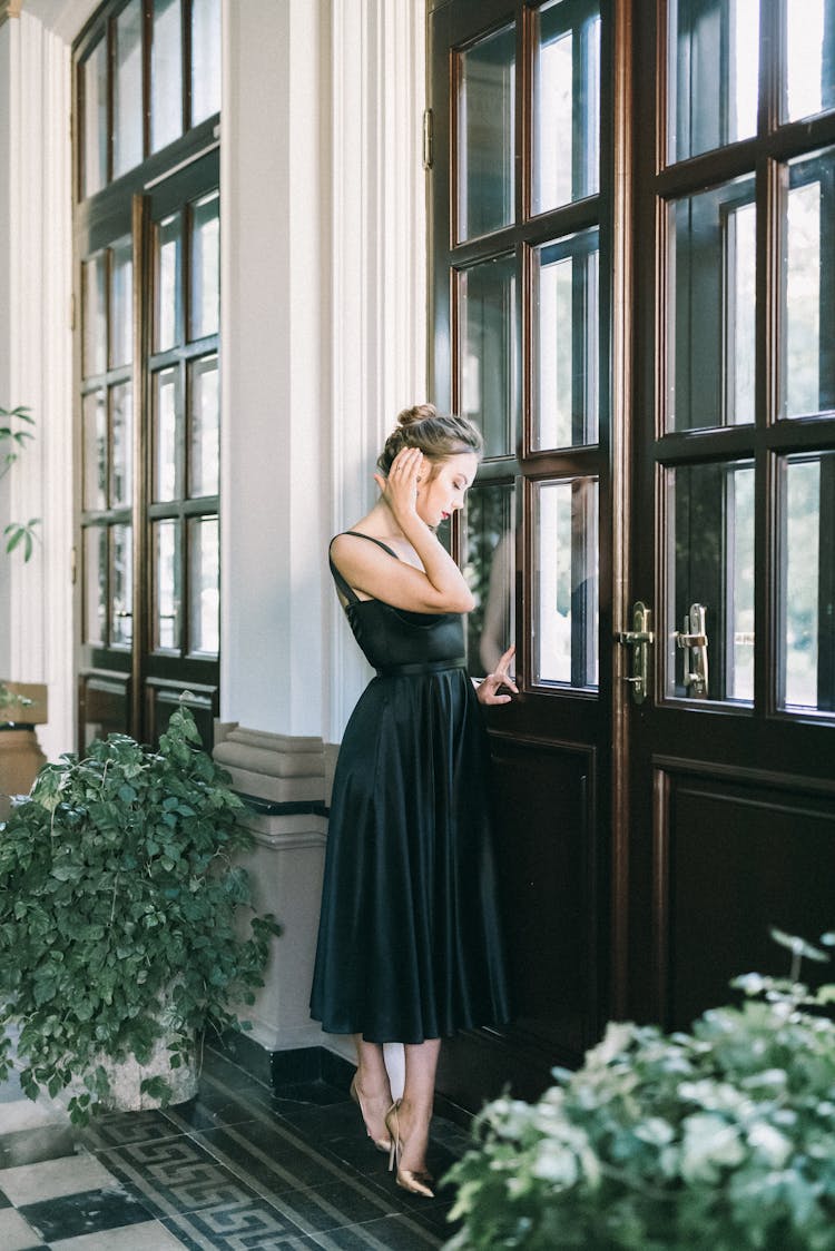 A Woman In Black Dress Standing Near Door