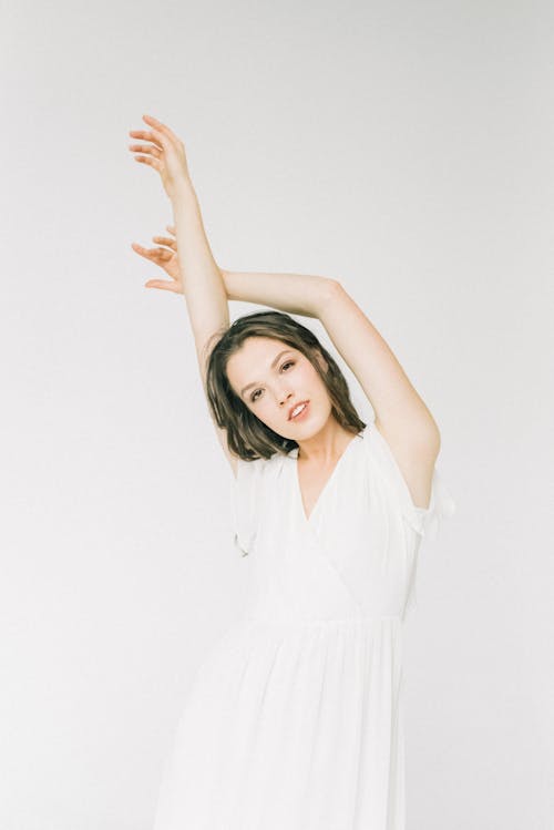 Free Woman in White Dress Stretching Her Arms while Posing at the Camera Stock Photo